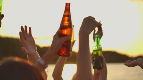 Teenagers-are-dancing-with-hands-up-with-beer.-This-is-perfect-party-at-sunset-on-the-lake-coast.